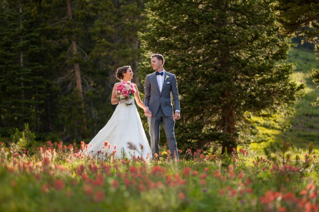 newlyweds walk among wildflowers on Colorado mountain.jpg