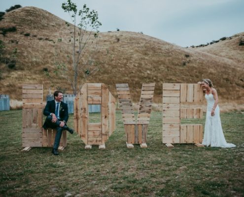 newlyweds play on giant LOVE wood sign