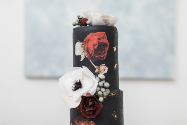 black wedding cake with white and red flowers