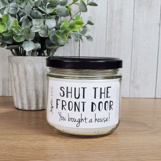 housewarming candle that says 'shut the front door'