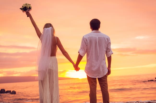 just married couple looking at sunset on beach