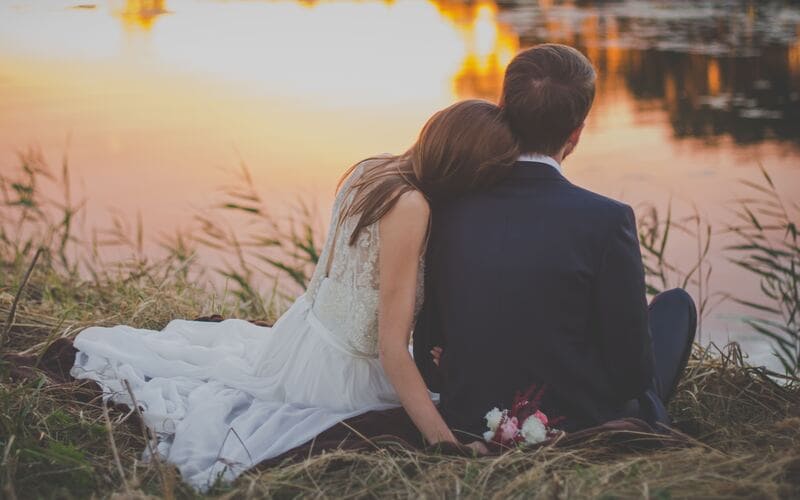 Bride and groom sit by pond